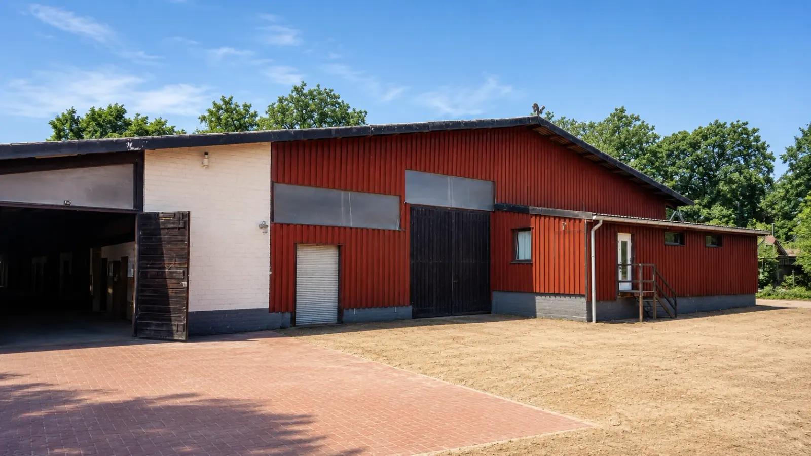 Stallgebäude mit roter Holzfassade und offenem Stalltor